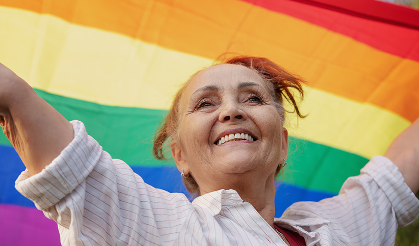 person holding LGBTQ+ pride flag over their head