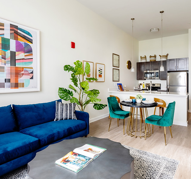 A fully furnished living room looking into the dining kitchen area.