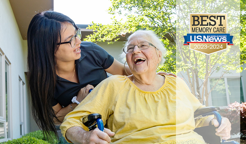 A caregiver laughing with a resident in the garden.