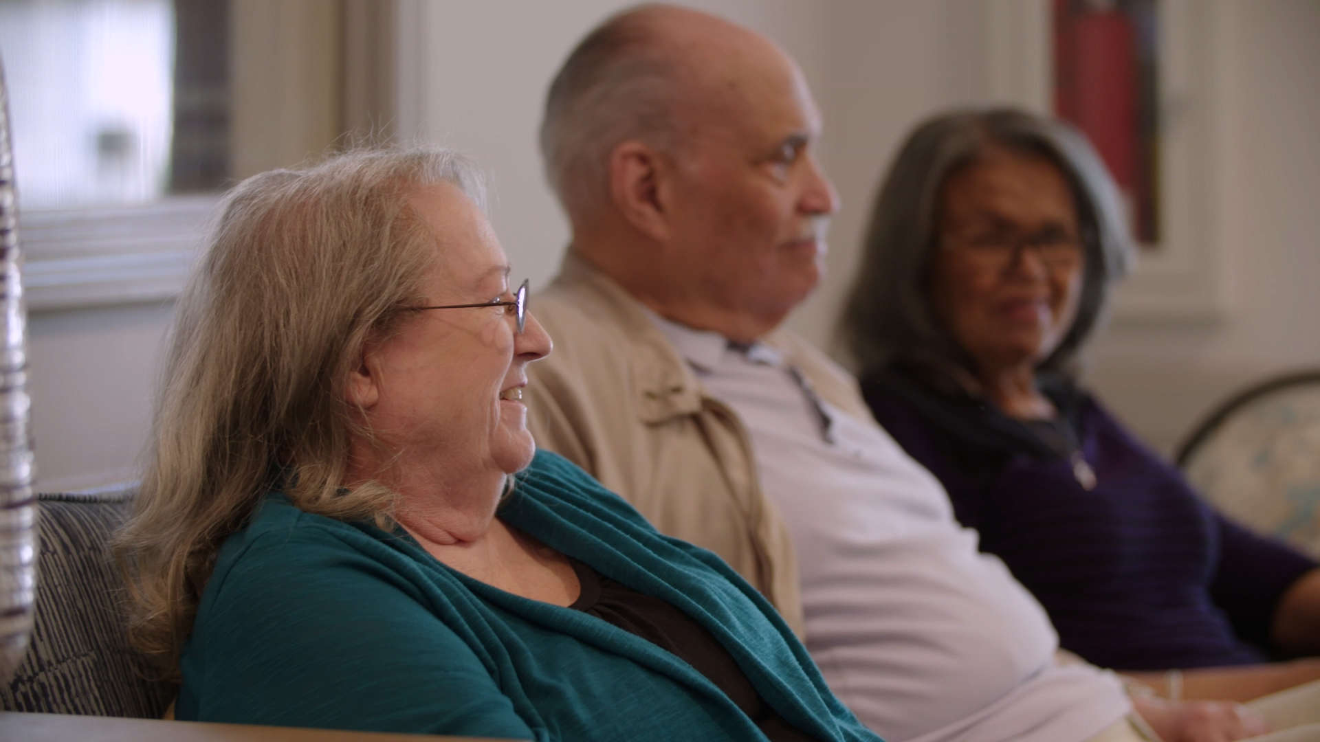 Three residents sitting on a couch and smiling.