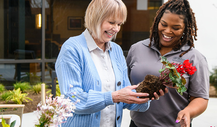 A watermark employee helping a woman at the garden bench.