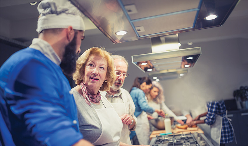 residents in the kitchen with a chef learning to cook