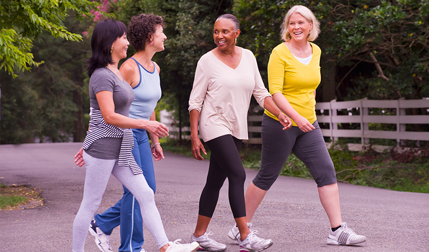 four friends smiling and walking outside together