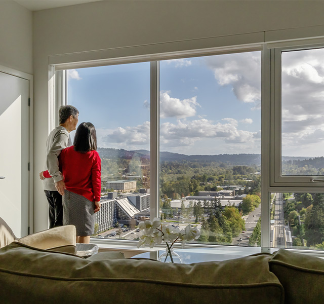 Two people standing by the window looking at the view.