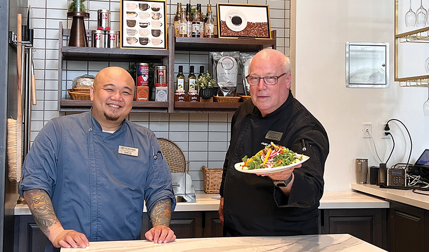 two chefs smiling and presenting food