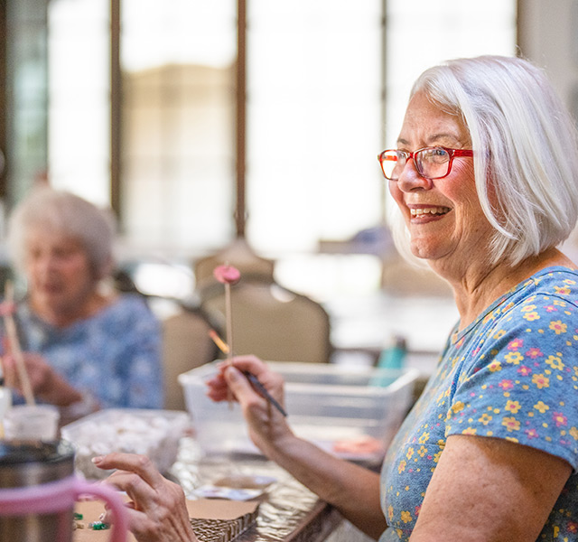 Residents enjoying an art class with canvases and paint brushes.