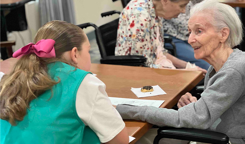 A resident at a table with a girlscout.