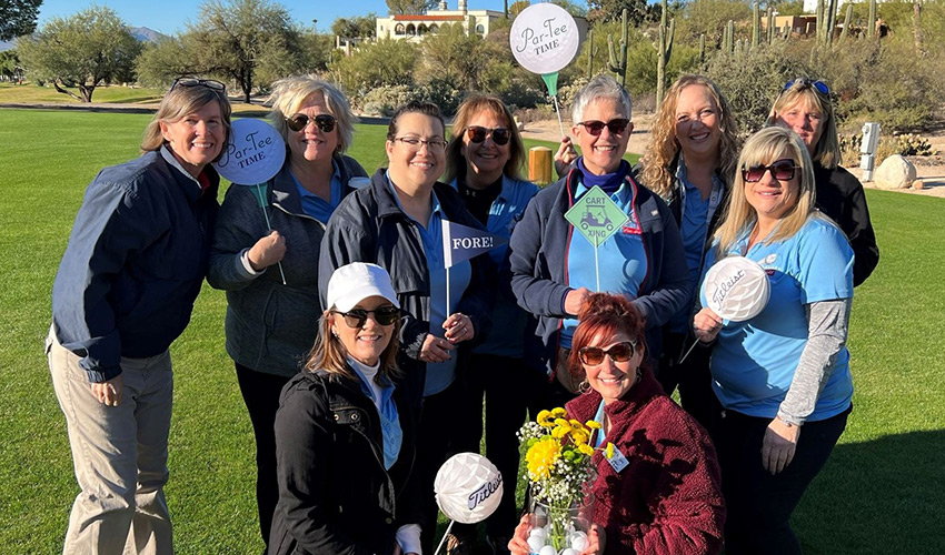 A group of people on the golf course holding signs.